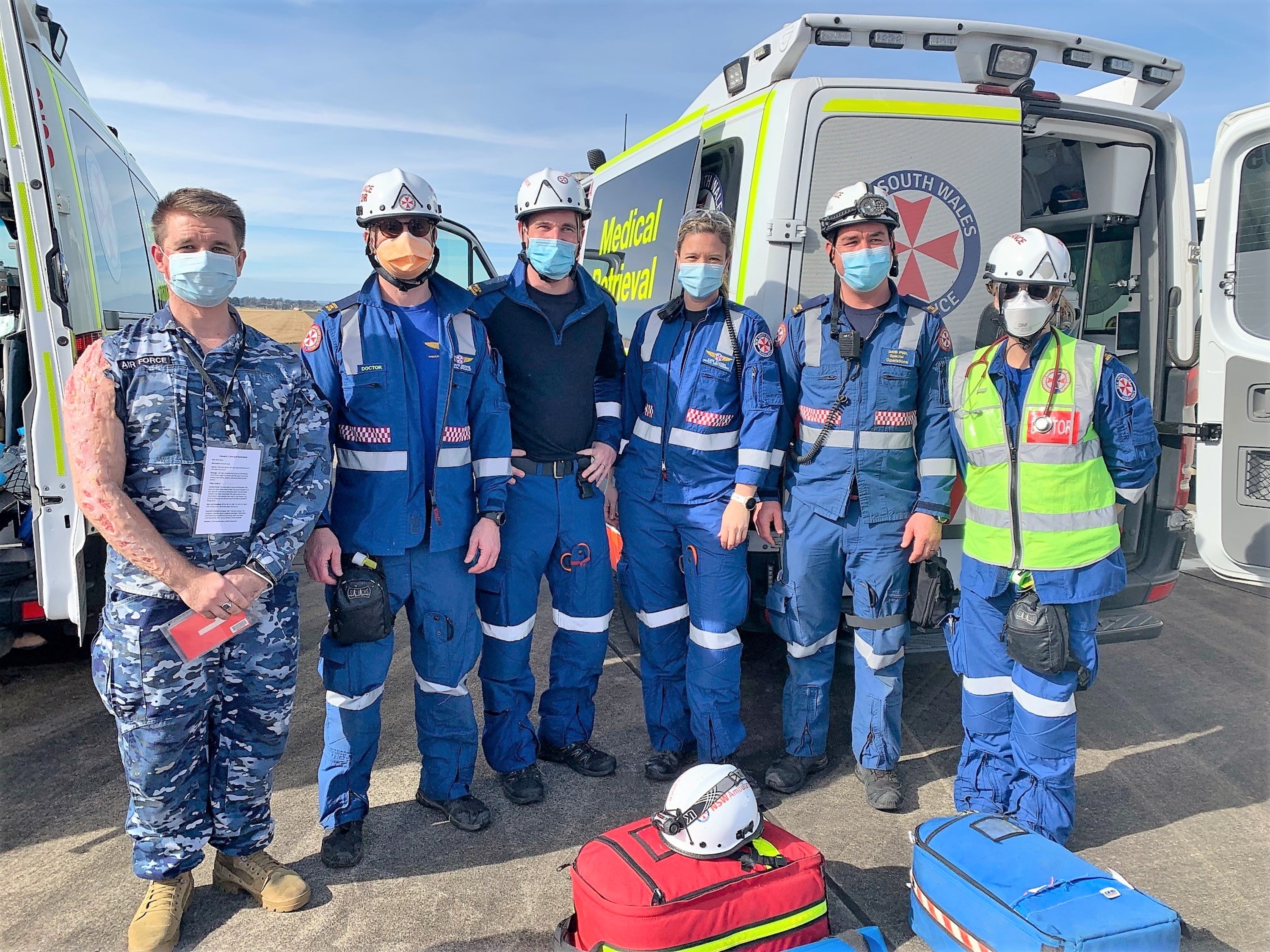 NSW Ambulance doctors and aeromedical staff posing for a group photo with an RAAF member in moulage at the multi-agency mass casualty exercise in June 2022.